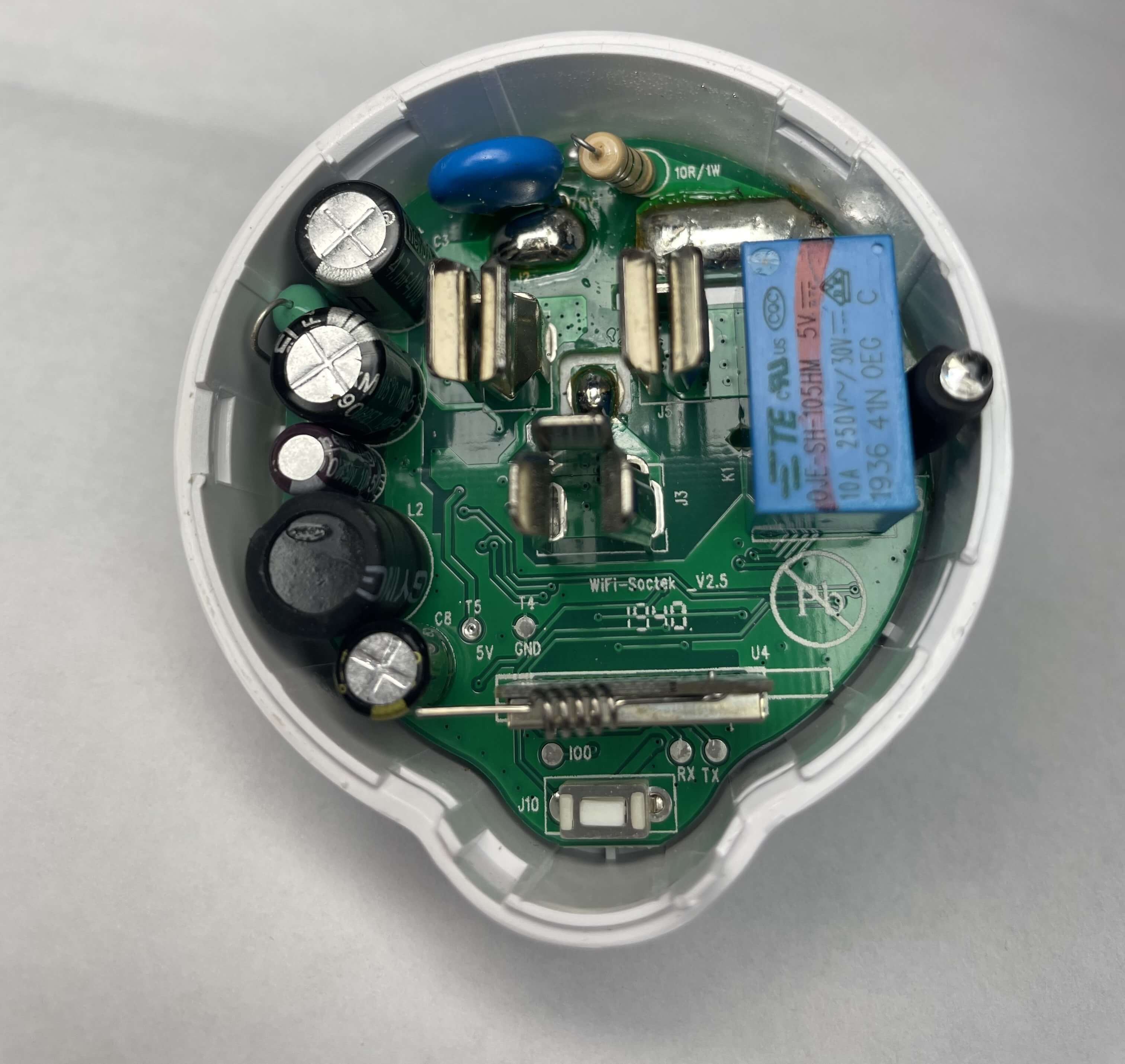 Etekcity Voltson ESW01-USA-R6P PCB A top-down view of the Etekcity Voltson ESW01-USA-R6P's PCB. At the bottom of the PCB, there is an AI-Thinker ESP 01E module identifiable by its spring antenna. Below the ESP module, there are three test pads labeled, from left to right, as IO0, RX, and TX. Above and to the left of the ESP module, there are two test pads labeled, from left to right, as T5/5V and T4/GND.